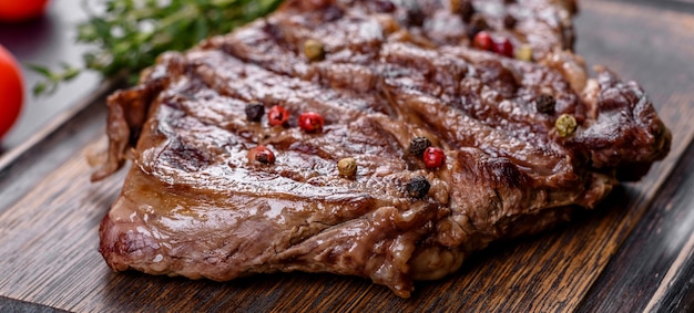 Delicious juicy fresh beef steak with spices and herbs on a dark concrete background. Grilled dishes