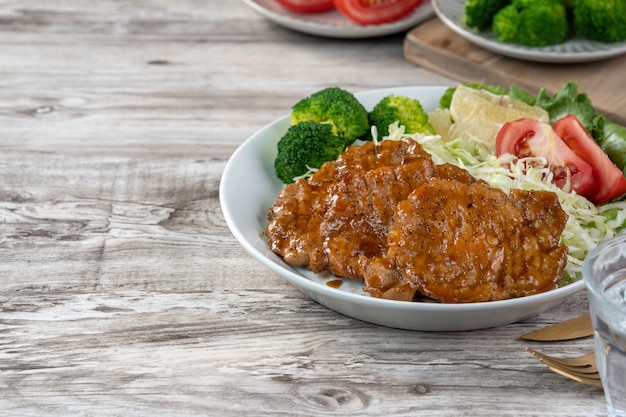 Delicious juicy pork chops with vegetables meal in a plate on dining table.