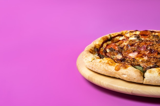 Delicious large pizza with bacon and spinach on a pink background.