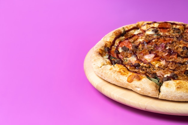 Delicious large pizza with bacon and spinach on a pink background