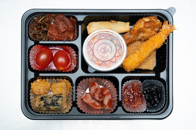 A delicious-looking lunch box with a variety of side dishes, fruits and tempura