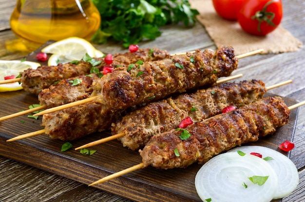 Delicious lula kebab on a wooden table. Chopped meat on wooden skewers, grilled. Eastern cuisine.