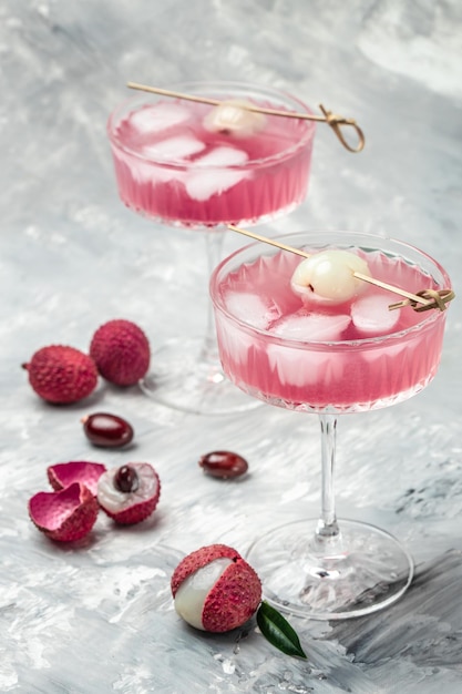 Delicious lychee cocktail in glass and fresh fruits vertical image top view place for text