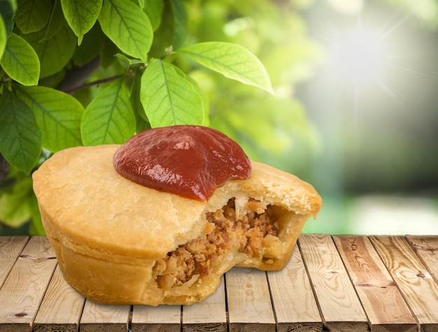 Delicious meat cake with sauce on wooden table with natural background