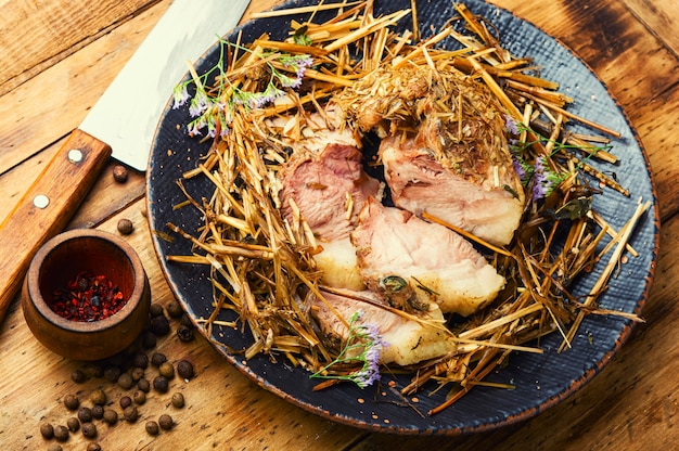 Delicious meat roasted in fresh hay. Baked pork meat in spicy herbs.Autumn food