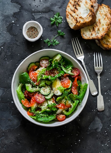 Delicious Mediterranean style salad with salmon egg vegetables lettuce and grilled bread on a dark background top view