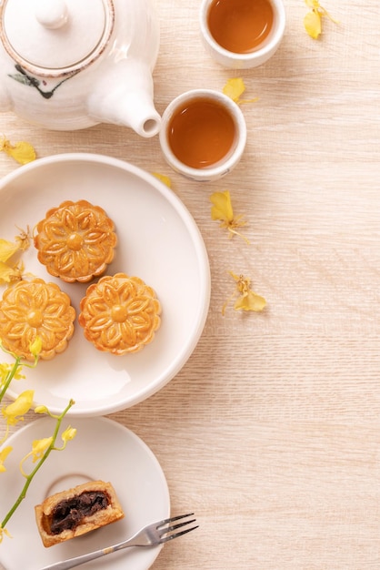 Delicious moon cake for MidAutumn festival with beautiful pattern decorated with yellow flowers and tea Concept of festive afternoon pastry design