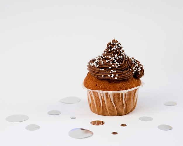 Delicious muffin and confetti on white background