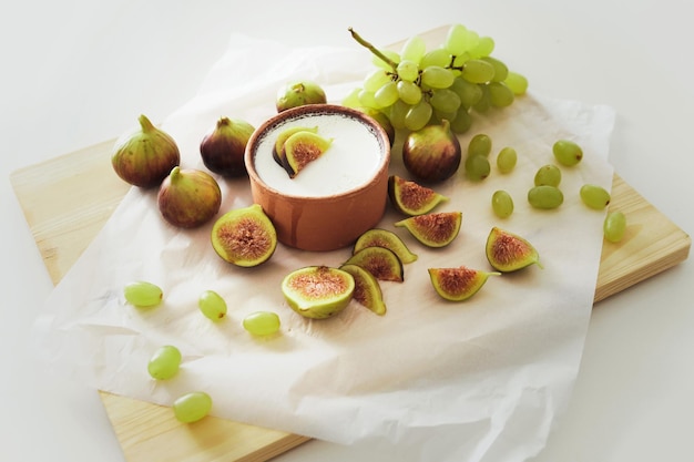 Delicious natural Greek yogurt in clay bowl with figs and grape