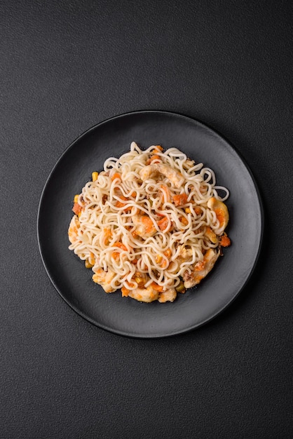 Delicious noodles with chicken and vegetables or udon on a black ceramic plate