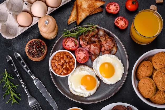 A delicious nutritious healthy breakfast with fried eggs bacon beans a glass of juice oat cookies milk and jam Healthy eating at the beginning of the day