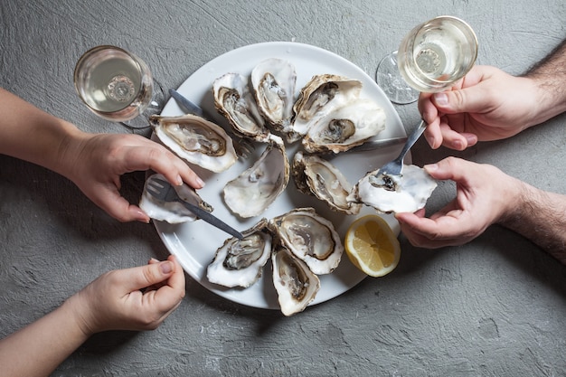 Delicious oysters with slice of lemon and glasses of white wine, top view