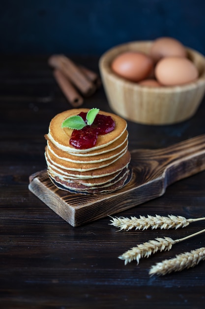 Delicious pancakes with jam and mint on a dark wooden table