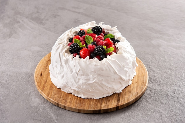 Delicious Pavlova cake with meringue topped and fresh berries on gray stone background