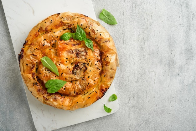 Delicious pie Spanakopita with soft feta cheese and spinach on old gray concrete table backgrounds Traditional Greek Spiral filo pastry pie spanakopita in shape of roll Traditional Greek cuisine