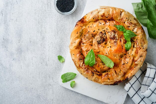 Delicious pie Spanakopita with soft feta cheese and spinach on old gray concrete table backgrounds Traditional Greek Spiral filo pastry pie spanakopita in shape of roll Traditional Greek cuisine