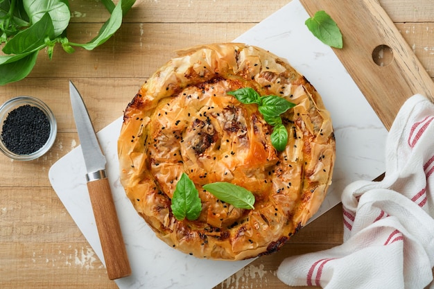 Delicious pie Spanakopita with soft feta cheese and spinach on old light wooden table backgrounds Traditional Greek Spiral filo pastry pie spanakopita in shape of roll Traditional Greek cuisine