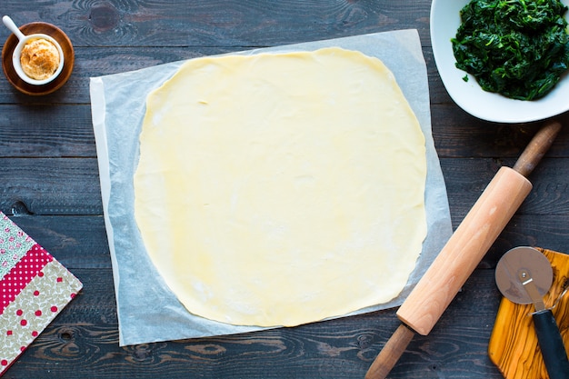 Delicious pie with spinach, made at home, on a wooden background,