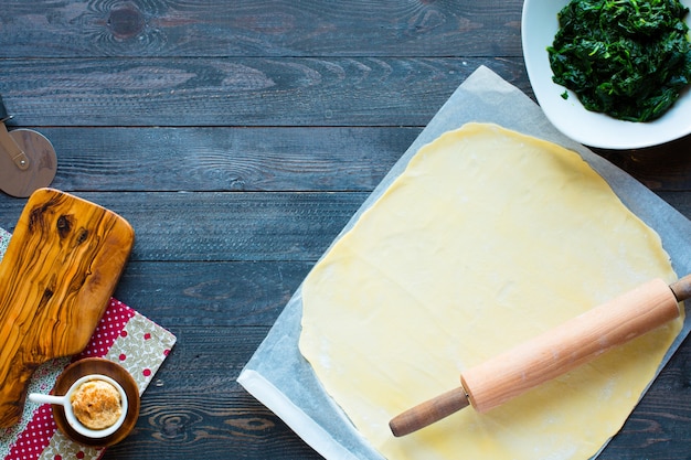 Delicious pie with spinach, made at home, on a wooden background