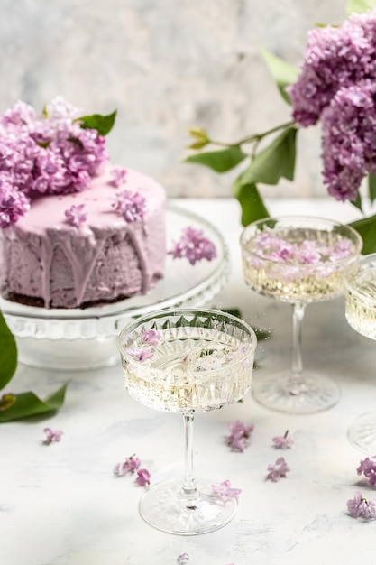 Delicious prosecco champagne wine with berry mousse cake bouquet of purple blooming lilacs French cuisine postcard background