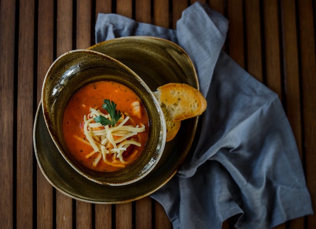 Delicious pumpkin soup with heavy cream on dark rustic wooden table