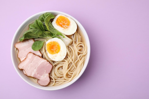 Delicious ramen with meat on violet background top view and space for text Noodle soup