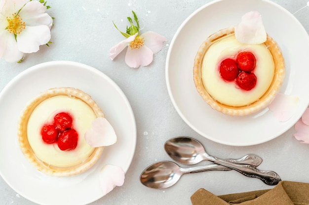 Delicious red raspberry strawberry whipped creamy tartletscakesgourmet confection dessert on plate with latte coffeemilksweet tasty pastry baked pie cheesecake with ripe berries on gray table