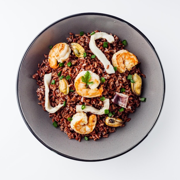 delicious red rice with shrimps and seafood on a white background