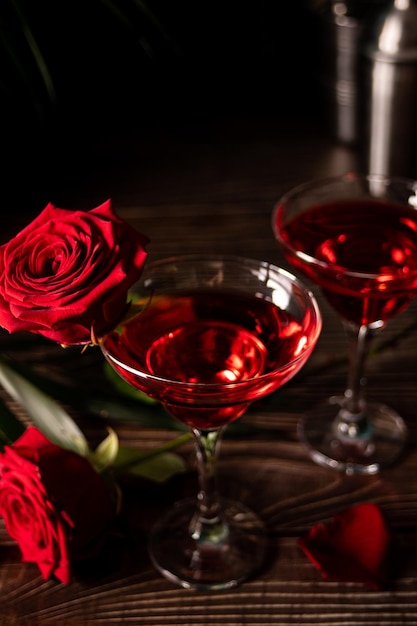 Delicious refreshing beverage drink red cocktail with red rose and petals on wooden table Romantic Valentines day concept