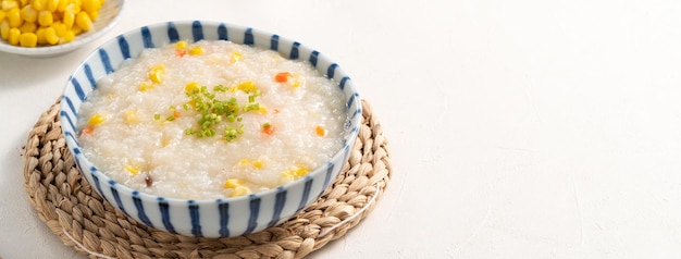 Delicious rice porridge congee with corn kernel and vegetables on white table background