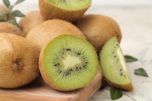 Delicious ripe lots of kiwi fruit and kiwi cut on a board on a light concrete background closeup