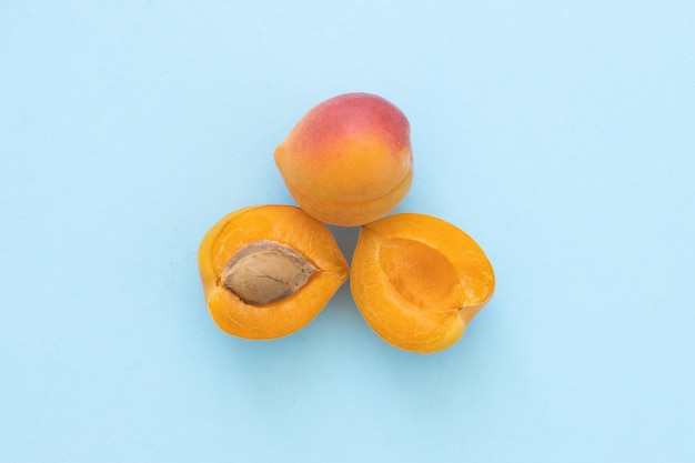 Delicious ripe sweet apricots on blue background flat lay Space for text