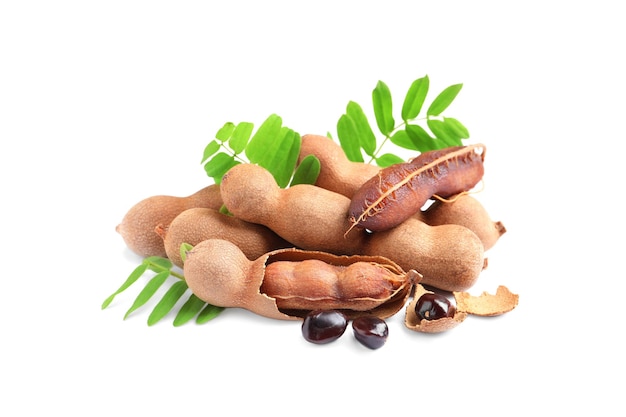 Delicious ripe tamarinds with leaves and seeds on white background Exotic fruit