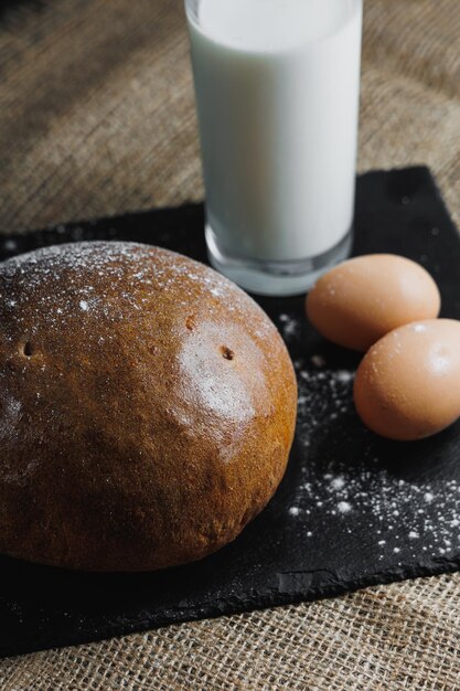 Delicious round rye bread with milk and eggs on a dark background Crispy fresh bread