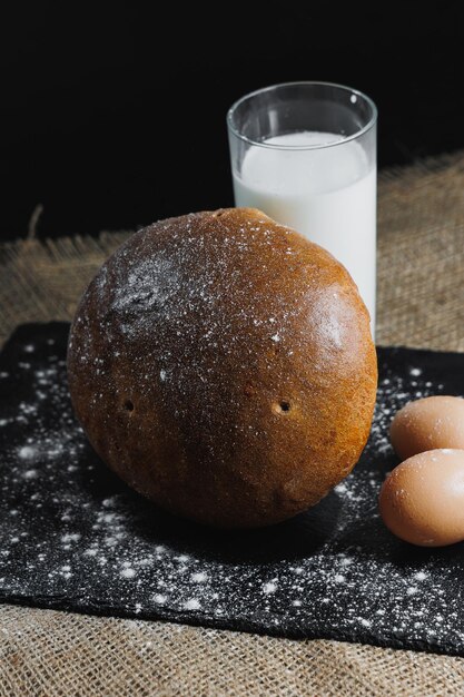 Delicious round rye bread with milk and eggs on a dark background Crispy fresh bread