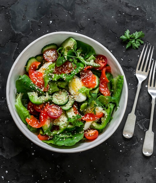 Delicious salad fresh salad with salted salmon egg vegetables lettuce on a dark background top view