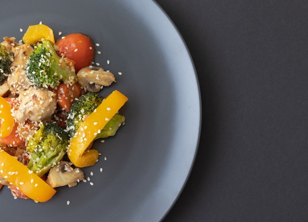 Delicious salad made of broccoli cherry tomatoes yellow pepper mushrooms pieces of chicken breast and sesame seeds