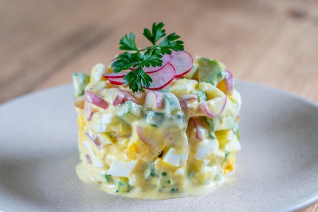 Delicious salad with cucumber radish and egg with cream sauce in a plate on wooden background Healthy food close up