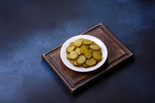 Delicious salted canned cucumbers cut into slices on a white ceramic plate