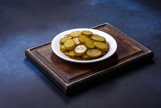 Delicious salted canned cucumbers cut into slices on a white ceramic plate