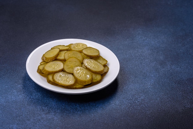 Delicious salted canned cucumbers cut into slices on a white ceramic plate