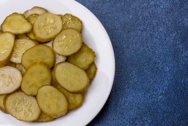 Delicious salted canned cucumbers cut into slices on a white ceramic plate