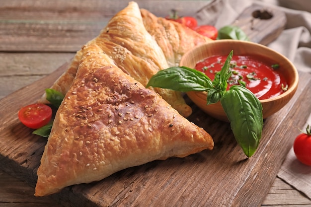 Delicious samsa with chicken meat and sauce on wooden table