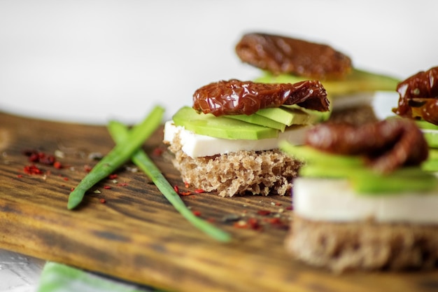 Delicious sandwiches with cheese avocado and dried tomatoes Closeup Concept for food healthy food and vegetarians