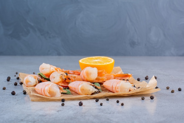 Delicious shrimps with sliced lemon and peppercorns on greaseproof paper 