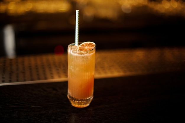 Delicious Singapore Sling cocktail with dried lime slice on the wooden bar counter