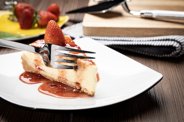 delicious slice of  strawberries cheesecake on a white plate on a wooden table