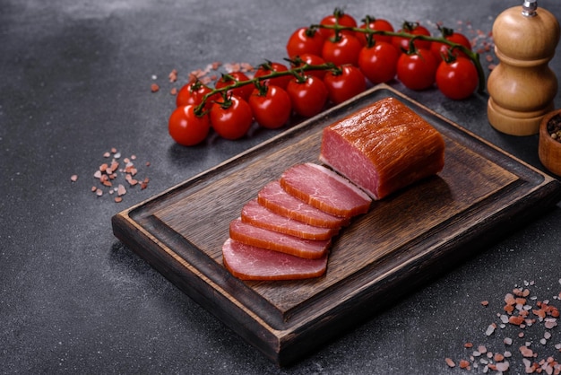 Delicious smoked meat cut with slices on a wooden cutting board