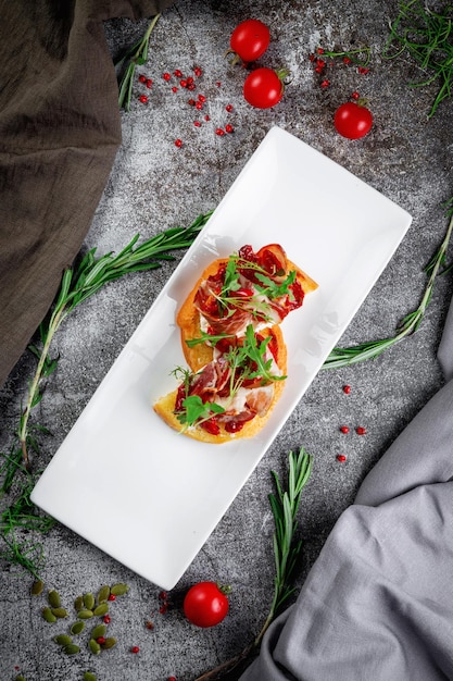 Delicious snacks Bruschetta with bacon roasted tomato red onion rings and arugula Toasted croutons with dried meat and lettuce