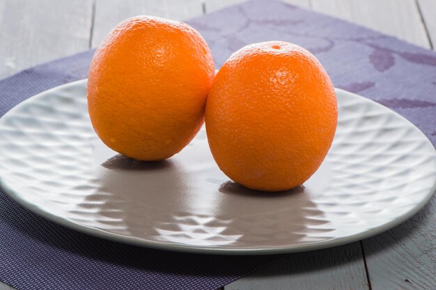 Delicious spanish orange on a wooden table one cut in halfFresh juicy oranges on the table